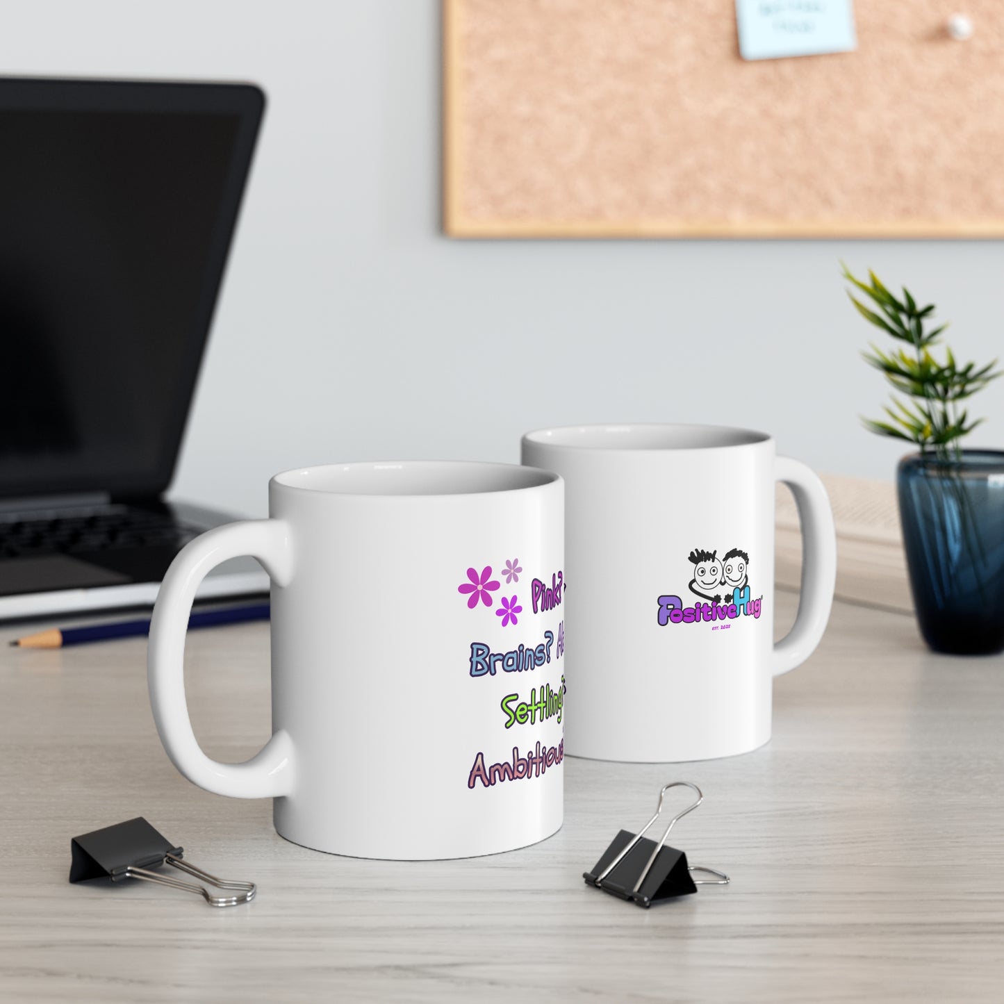 Two mugs with decorative designs on a desk with office supplies.