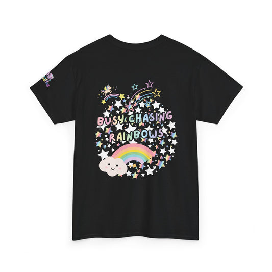 A black short-sleeve t-shirt with a colorful graphic on the front featuring the text 'BUSY CHASING RAINBOWS' surrounded by stars, a rainbow, and a cloud, shown on a plain white background.