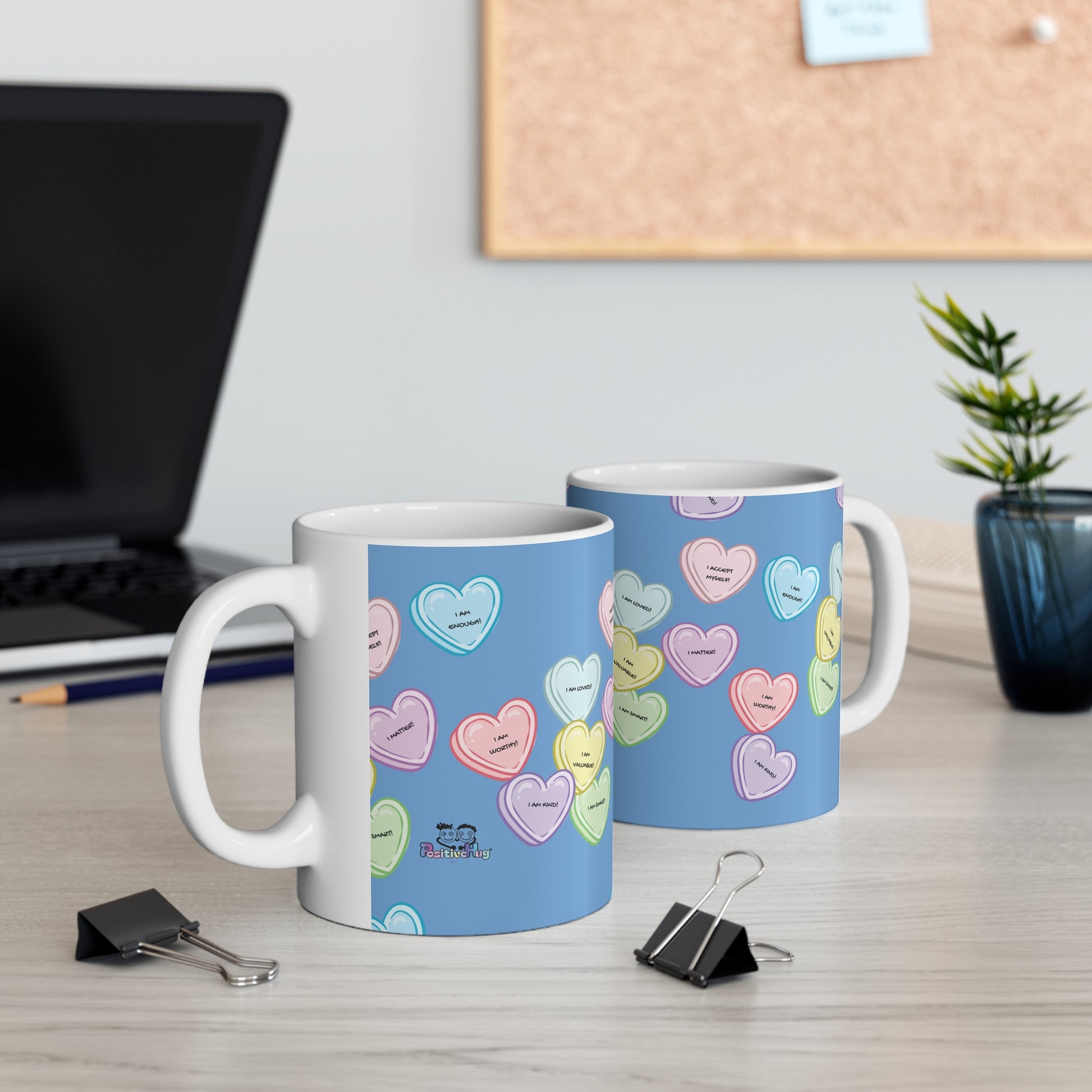 Two mugs with colorful heart pattern on a desk with office items.